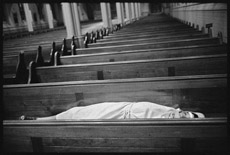 Photograph of person lying on church pew.