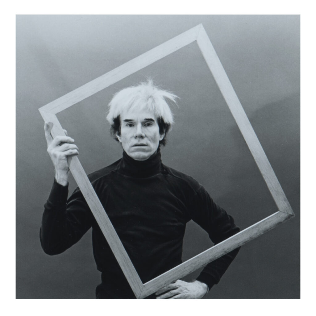 Andy Warhol holding an empty picture frame in front of himself